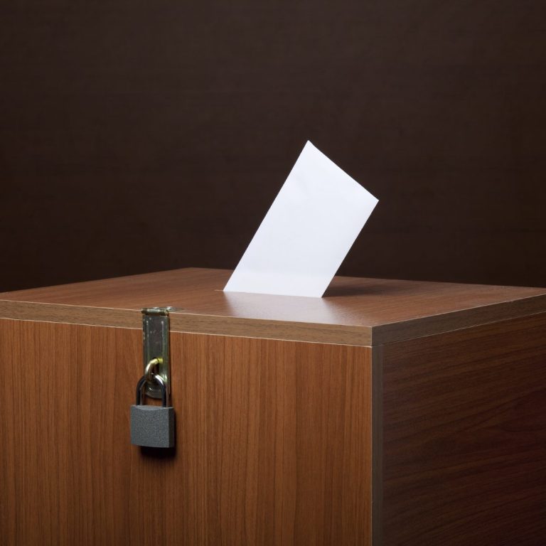 ein Umschlag steckt in einer Wahlurne